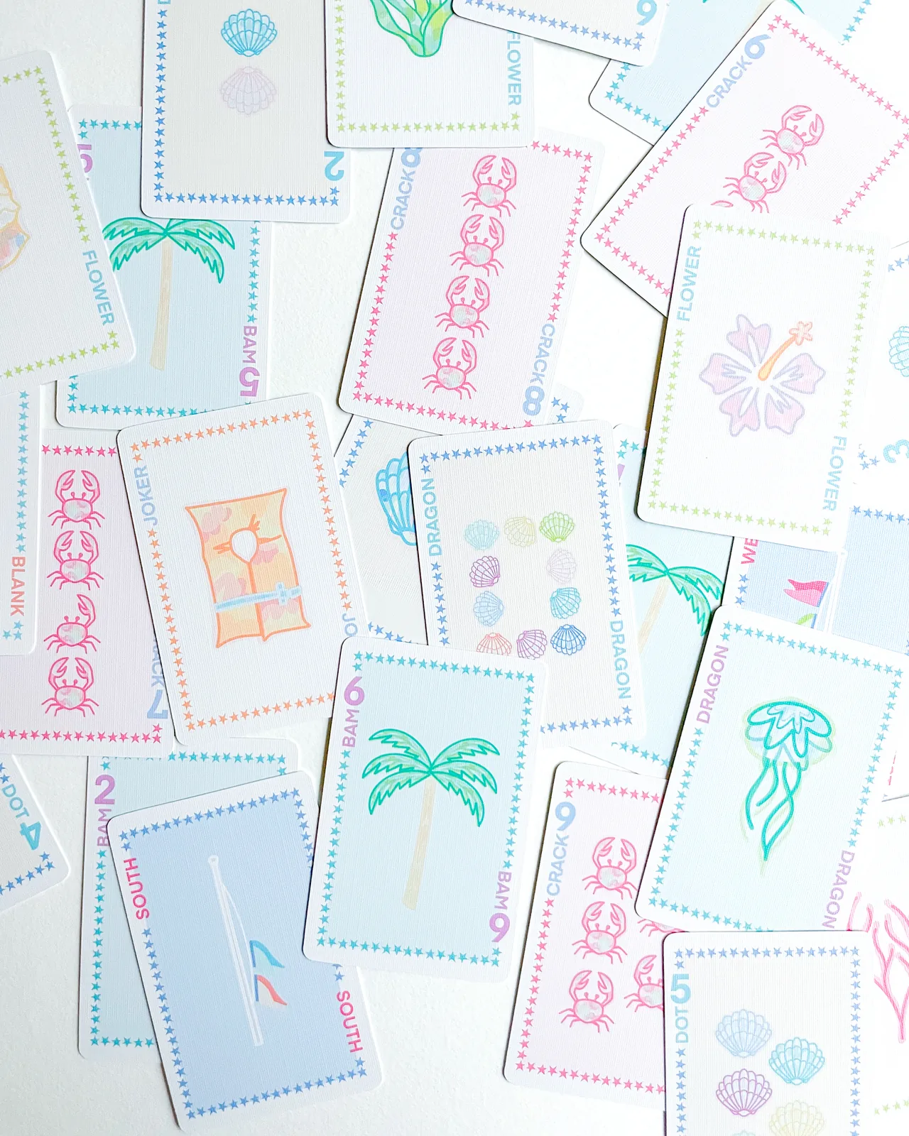 Beach Edition cards scattered face up: palms, crabs, shells and a hibiscus flower