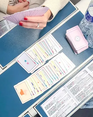 Hands holding a fan of cards over exposed hands and line cards on a navy table