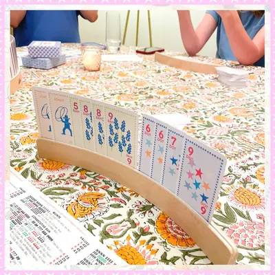 Hands playing with racks and cards on a floral tablecloth