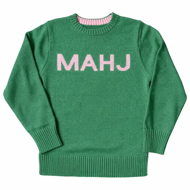 The MAHJ Knit Sweater in Green/Blush laid flat, with pink MAHJ letters knitted across the chest