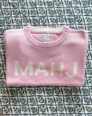 Pink MAHJ Knit Sweater folded on a blue and white block-print tablecloth