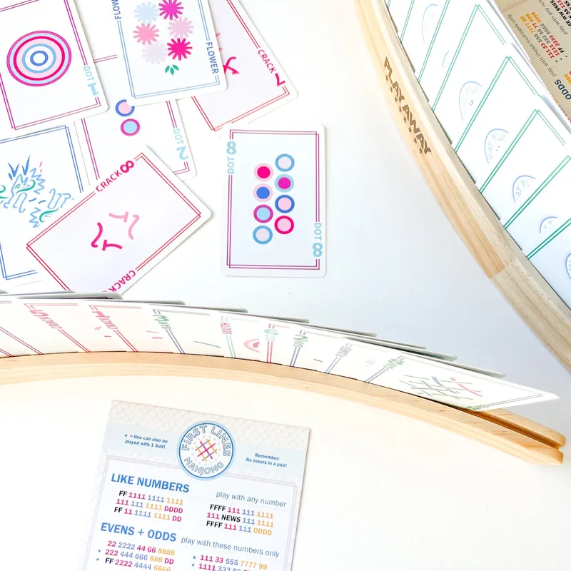 Overhead view of Play Away cards standing in two wooden racks beside a First Lines sheet